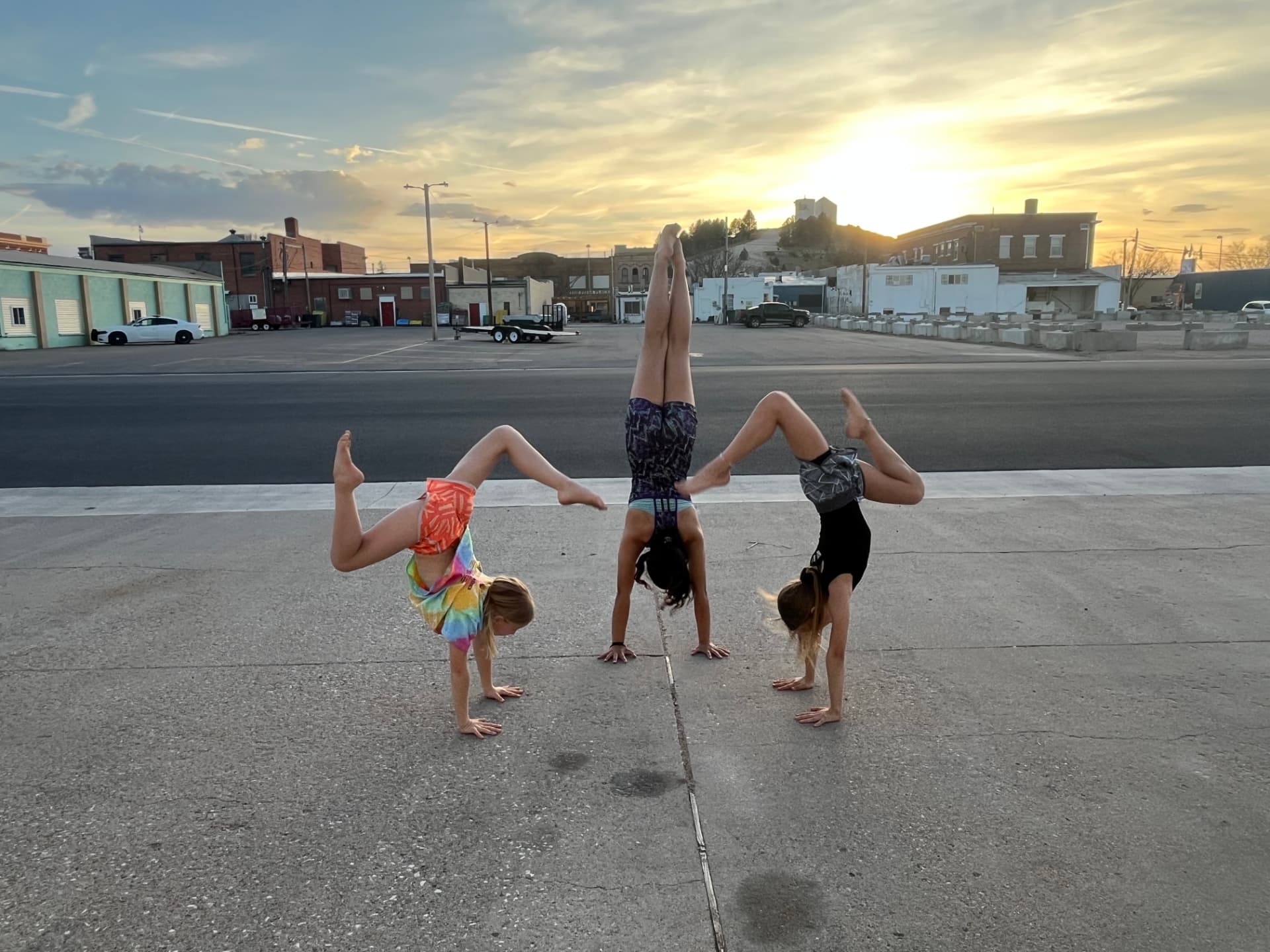 Three young gymnasts doing handstands at sunset in downtown Lusk